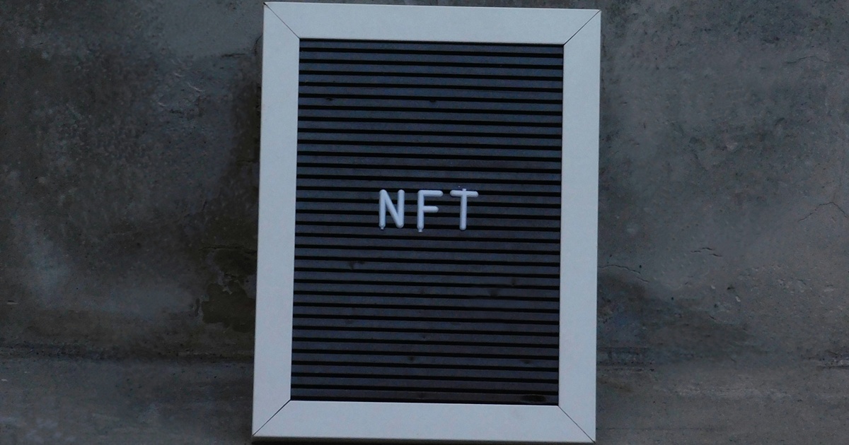 NFTの文字が書かれた黒いボードとコンクリート壁